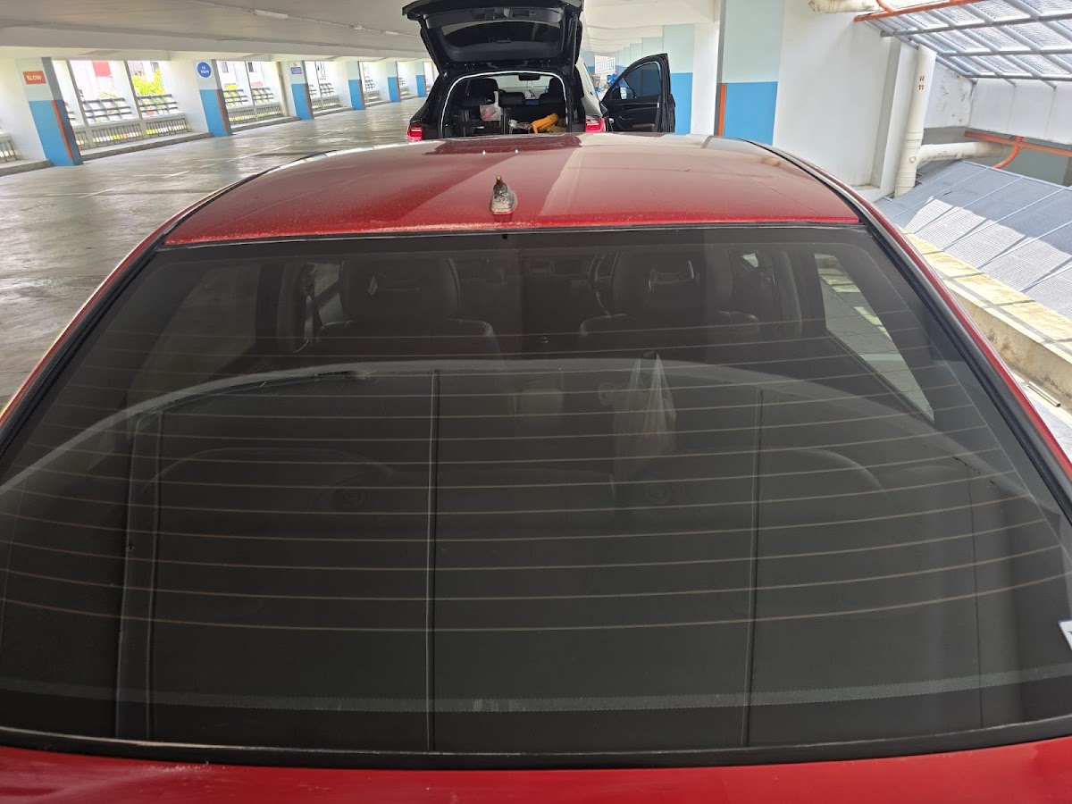 The rear screen of a red car, spotless after a glass polish
