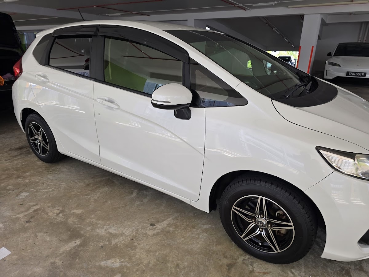 White Honda hatchback with freshly polished paintwork in a carpark